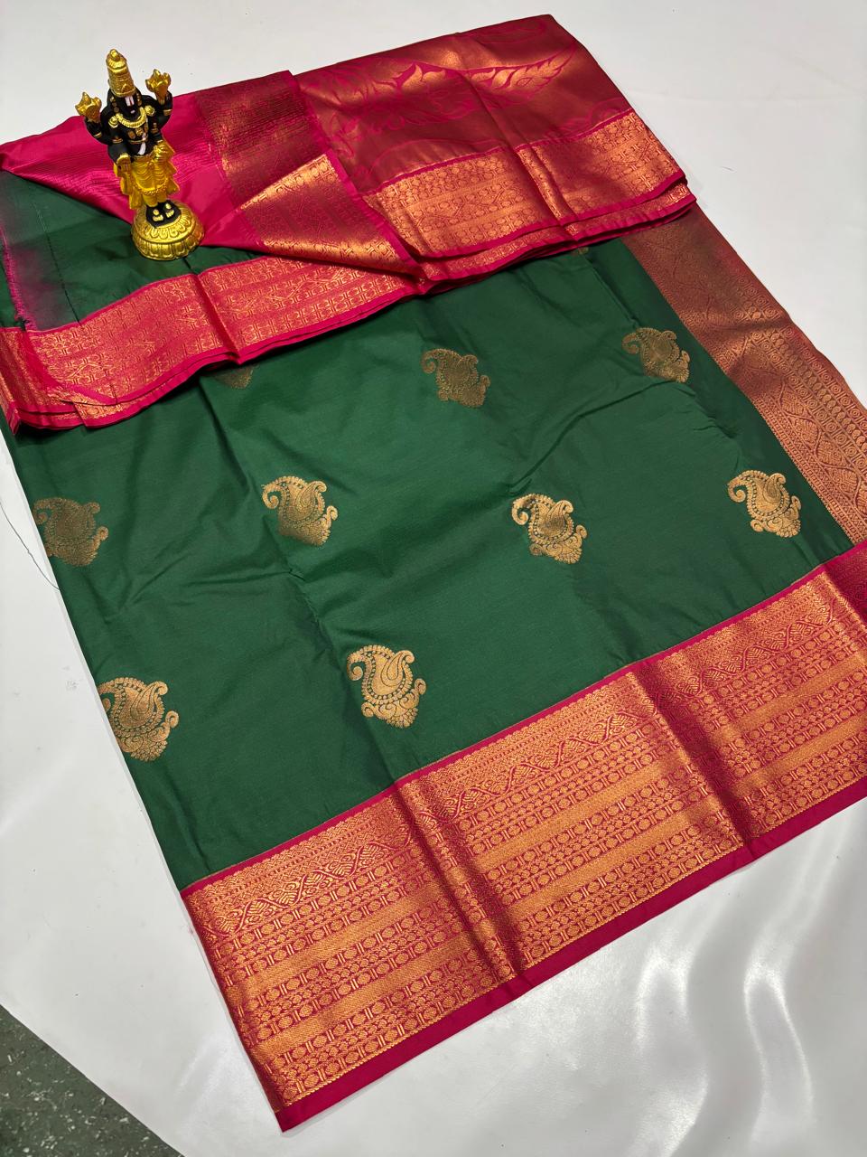 Bottle green Elampillai silk saree with a magenta pink zari border and gold mango motifs.