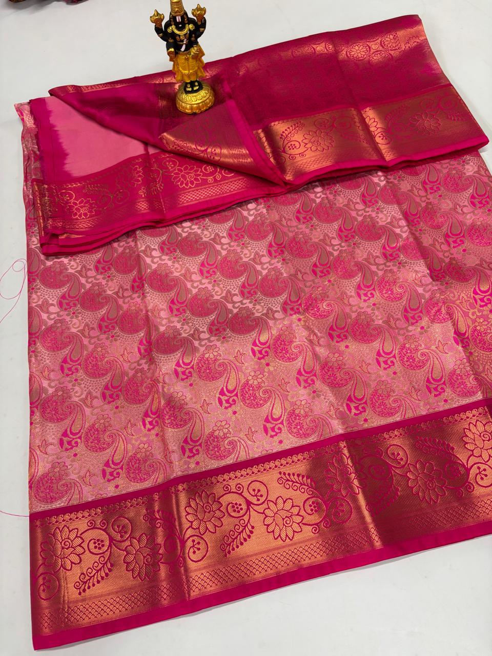 Blush pink silk saree with dense magenta paisley jaal and gold floral border.