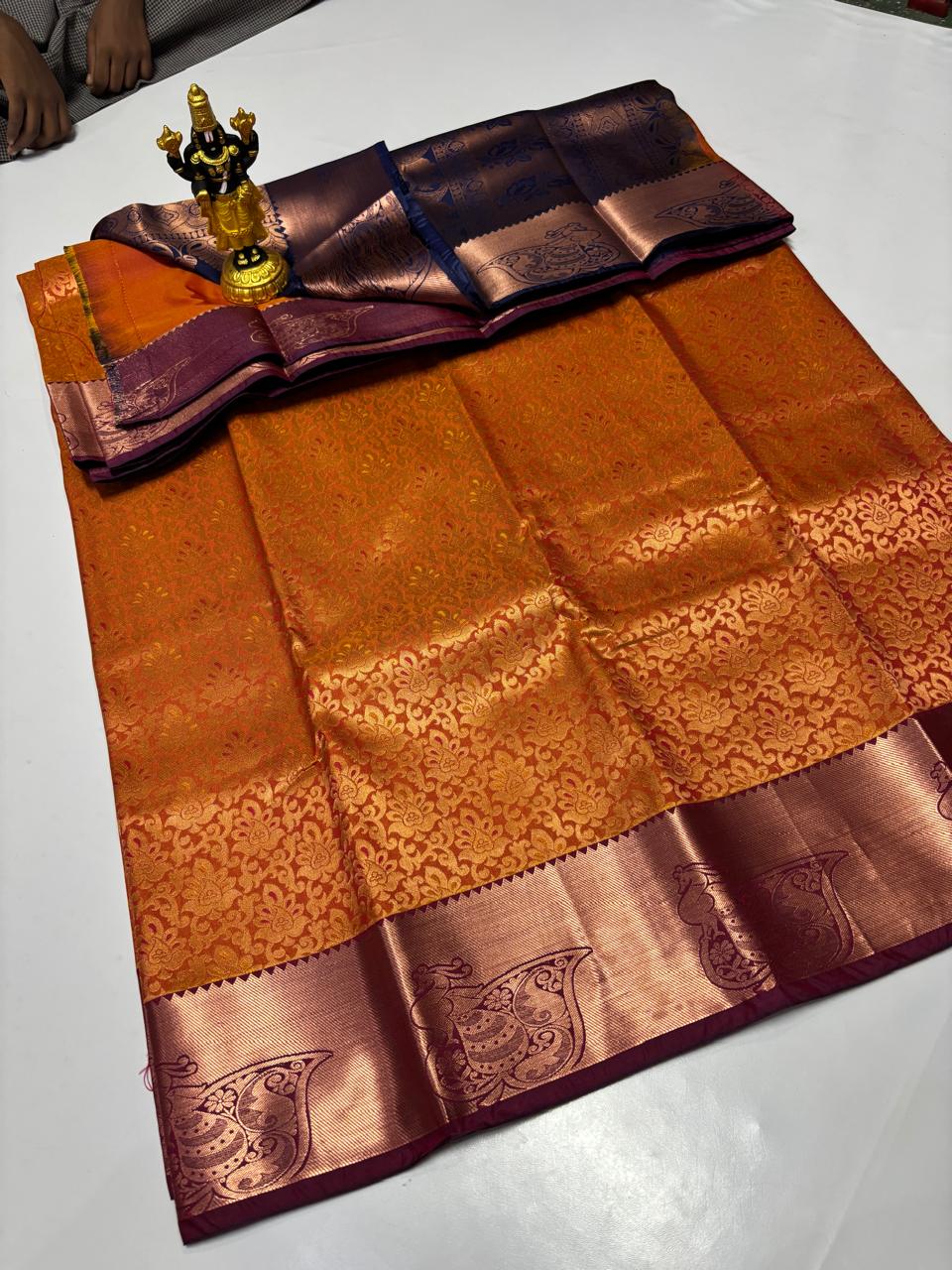 Amber orange Elampillai saree with burgundy peacock motif border.