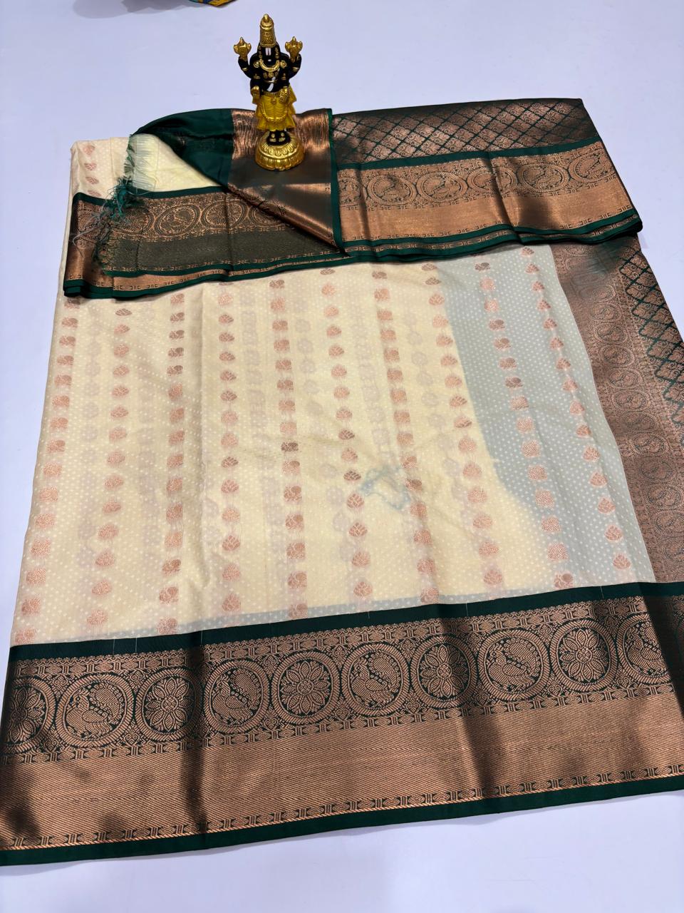 Cream colored Elampillai silk saree with dark green border and circular floral zari motifs.